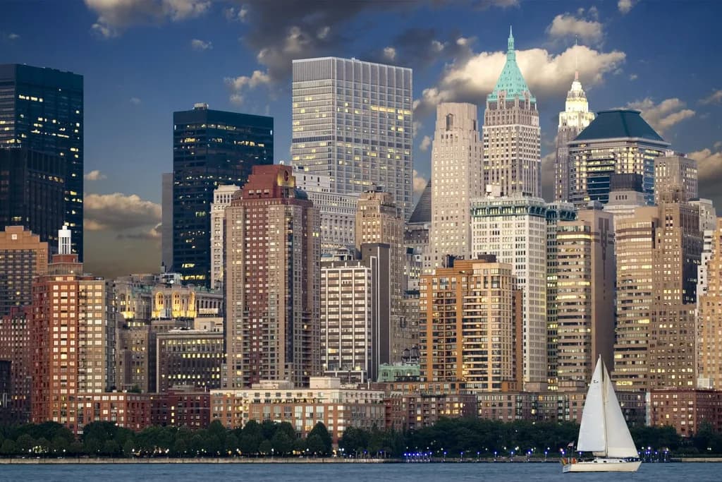 Lower Manhattan financial district skyline across the water, with a sailboat in the harbor